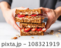 hand holding a delicious-looking almond butter whole grain toast sandwich 108321919