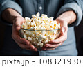 hand holding a clear bowl of air-popped popcorn 108321930