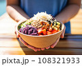 hand holding an acai bowl with a backdrop of natural sunlight 108321933