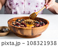 hand placing a spoon into an acai bowl with honey swirls 108321938