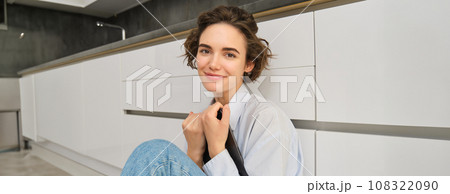 Image of happy young woman sits at home on floor, holds digital tablet, does online shopping, reading e-book 108322090