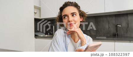 Portrait of beautiful woman at home, holding smartphone, online shopping from mobile phone app 108322397