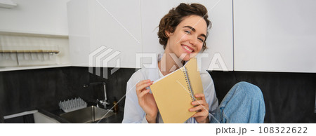 Indoor shot of young woman relaxing at home, reading journal, studying in comfort, spending time inside her house 108322622
