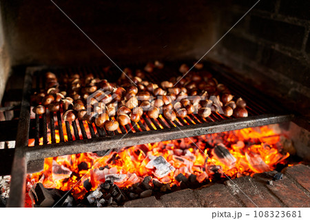 Fresh chestnuts are baked on hot coals on a grill in the oven 108323681