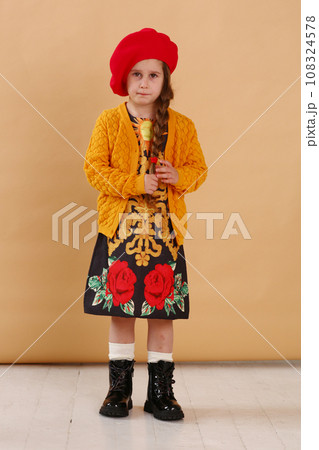 little model girl in designer dress, red hat and military boots full body photo walking 108324578