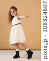 little model girl with long brown hair in designer white dress with belt, military boots full body photo walking. 108324607