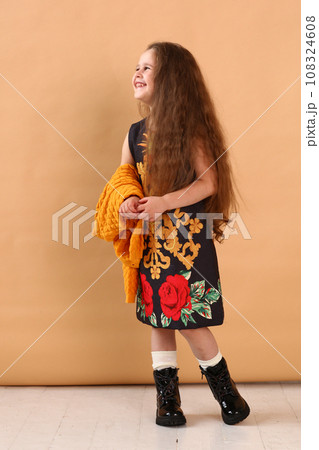 little model girl with long brown hair in designer floral dress, yellow jacket and military boots  108324608