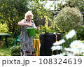 pensioner blond woman with water can on beautiful garden background closeup photo 108324619