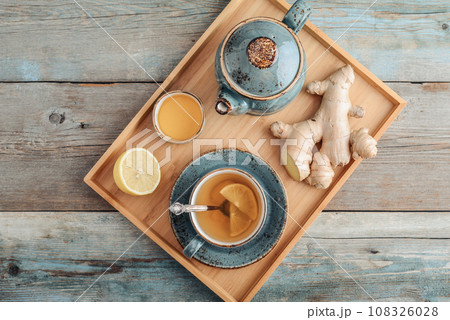 Ginger tea with lemon and honey in a blue cup on a bamboo tray Ginger tea with lemon and honey in a blue cup on a bamboo tray 108326028