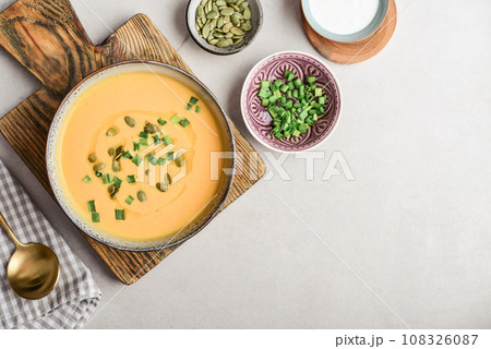 Pumpkin soup in a bowl with pumpkin seeds, green onions and breadsticks 108326087