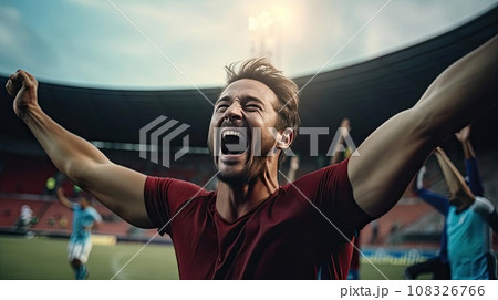 Happy man raising his hands in the air at a football game 108326766