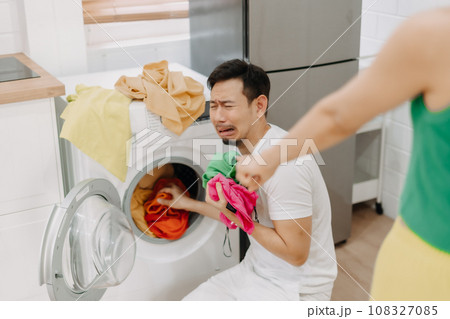 Funny man crying being force by his wife to wash clothes and do housework. 108327085