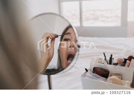 Woman wearing make up at the mirror with tools and equipments. Woman wearing make up at the mirror with tools and equipments. 108327116