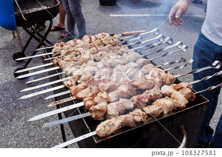 Traditional Turkish kebab on hot burning grill with skewers outdoors cooking Traditional Turkish kebab on hot burning grill with skewers outdoors cooking 108327581