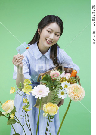 Recycled items_Picture of a korean asain beautiful woman holding a recycled credit card among flowers. 108328209