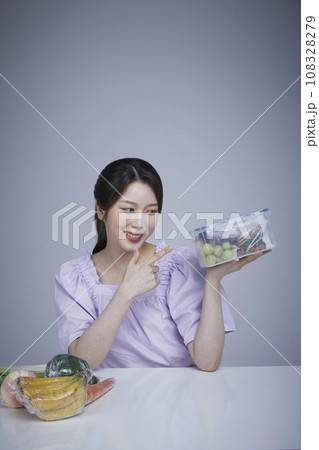 Image of a korean asain beautiful woman holding a plastic tub of fruits and vegetables wrapped in saran wrap. 108328279