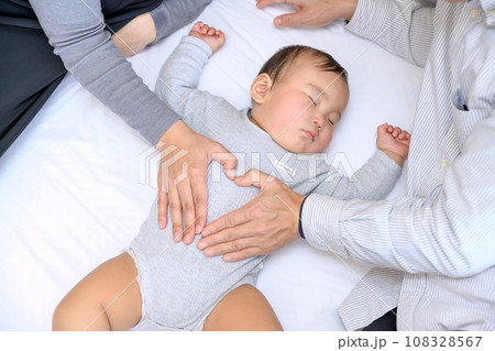 赤ちゃんと添い寝して手でハートをつくる父親と母親 乳幼児 寝かしつけ 添い寝 育児休暇 0歳乳幼児 赤ちゃんと添い寝して手でハートをつくる父親と母親 乳幼児 寝かしつけ 添い寝 育児休暇 0歳乳幼児 108328567