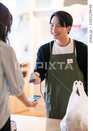 スマホのアプリ画面を読み取る男性店員 スマホのアプリ画面を読み取る男性店員 108329648
