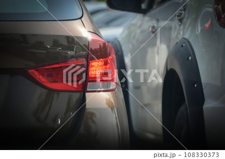 red tail light of brown car in large asphalt parking lot, transportation industry 108330373
