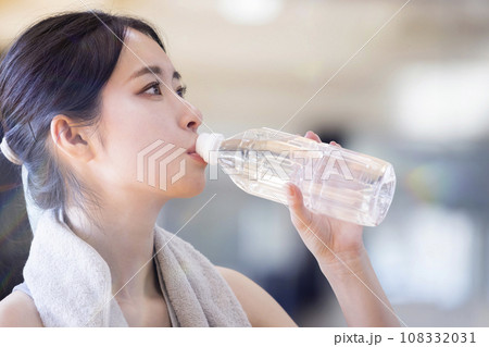 スポーツジムでペットボトルの水を飲む若い女性 108332031