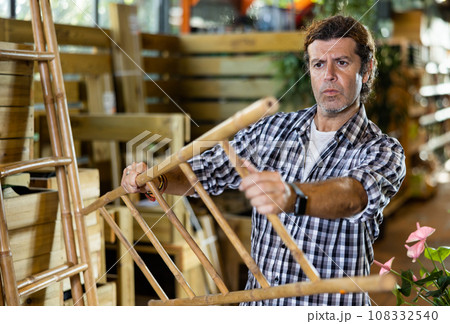 European gardener is attentively examining a bamboo ladder 108332540