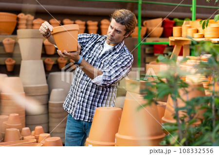 Interested amateur gardener looking for flowerpots at garden market Interested amateur gardener looking for flowerpots at garden market 108332556
