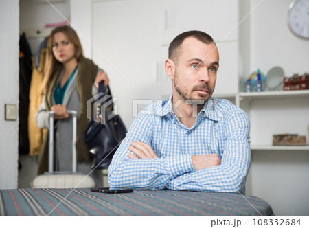 Frustrated man at table on background with woman leaving him Frustrated man at table on background with woman leaving him 108332684