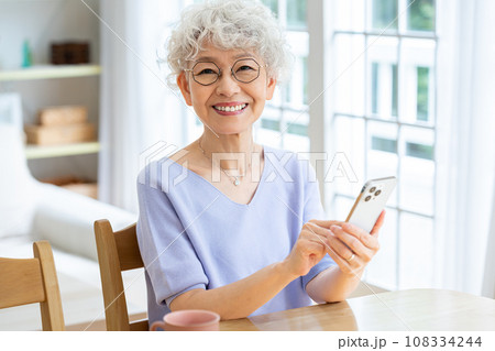 リビングでスマホを操作するシニア女性 リビングでスマホを操作するシニア女性 108334244