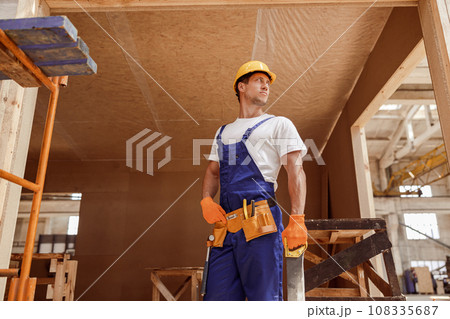 Handsome man builder standing at house building construction site Handsome man builder standing at house building construction site 108335687