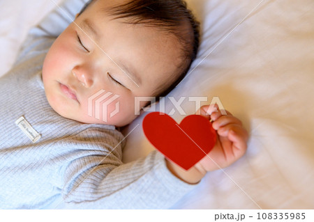 手にハートを持つベッドで寝る赤ちゃん 乳幼児 寝かしつけ 昼寝 寝顔 育児休暇 0歳乳幼児 手にハートを持つベッドで寝る赤ちゃん 乳幼児 寝かしつけ 昼寝 寝顔 育児休暇 0歳乳幼児 108335985