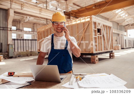 Cheerful male builder talking on cellphone at work 108336209