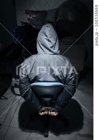 The man was sitting on a chair with tied hands in handcuffs The man was sitting on a chair with tied hands in handcuffs 108338669