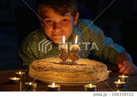 Happy blond little kid boy celebrating his birthday. Preteen child blowing candles on homemade baked cake, indoor. Birthday party for school children, family celebration Happy blond little kid boy celebrating his birthday. Preteen child blowing candles on homemade baked cake, indoor. Birthday party for school children, family celebration 108338722