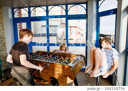 Little preschool girl and two kids school boys playing table soccer. Happy excited positive children having fun with family game with siblings or friends. 108338756