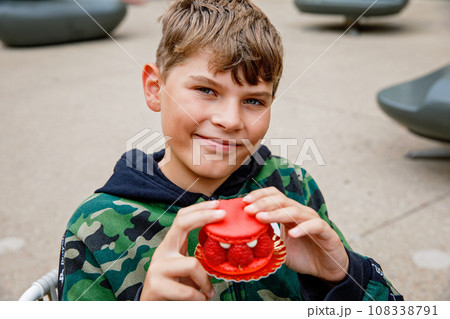Adorable kid boy and delicious raspberry cake. Preteen school child eating sweet dessert in French outdoor cafe. Adorable kid boy and delicious raspberry cake. Preteen school child eating sweet dessert in French outdoor cafe. 108338791