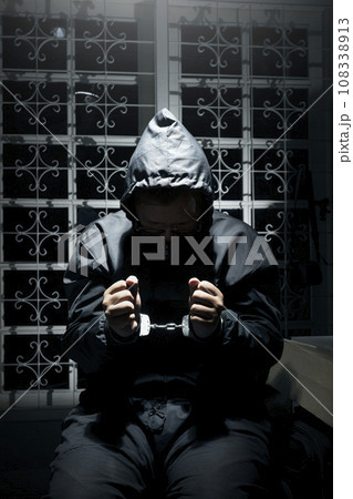 The man was sitting on a chair with tied hands in handcuffs The man was sitting on a chair with tied hands in handcuffs 108338913