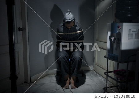 The man was sitting on a chair with tied hands in ropes The man was sitting on a chair with tied hands in ropes 108338919