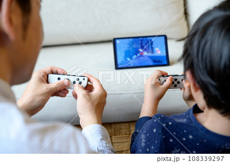 父親と家庭用ゲーム機で遊ぶ子ども　対戦　仲良し　家庭　イクメン　リモートワーク　 108339297