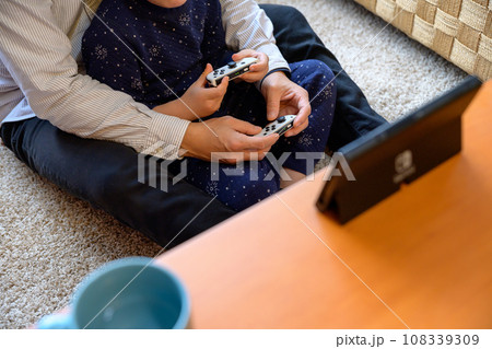 父親と家庭用ゲーム機で遊ぶ子ども　対戦　仲良し　家庭　イクメン　リモートワーク　 108339309