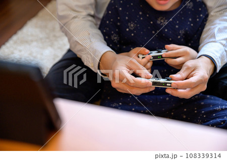 父親と家庭用ゲーム機で遊ぶ子ども　対戦　仲良し　家庭　イクメン　リモートワーク　 108339314