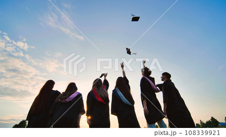 Student graduates toss their caps at sunset. Student graduates toss their caps at sunset. 108339921