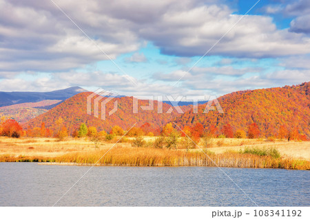 mountainous countryside landscape with lake in autumn. scenery in fall colors. bright sunny weather with clouds on the sky mountainous countryside landscape with lake in autumn. scenery in fall colors. bright sunny weather with clouds on the sky 108341192