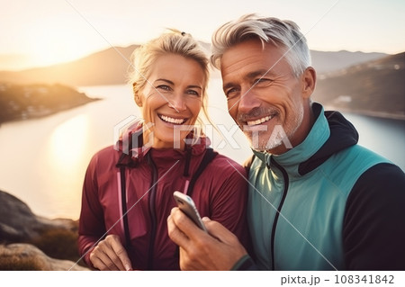 happy adult couple doing sports in the mountains and taking selfies on the phone, sharing photos on social networks, doing blogging 108341842