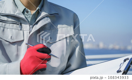 クリップボードを持つ作業服の男性・海と工業地帯│建設業・製造業・プラント　イメージ 108343933