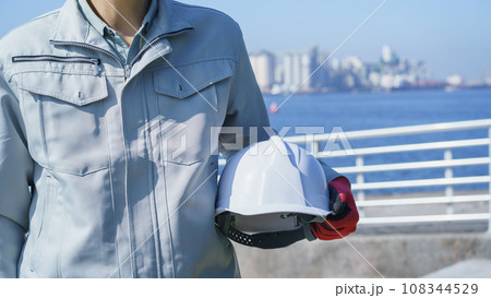 ヘルメットと作業服の男性・海と工業地帯│建設業・製造業・プラント イメージ ヘルメットと作業服の男性・海と工業地帯│建設業・製造業・プラント イメージ 108344529