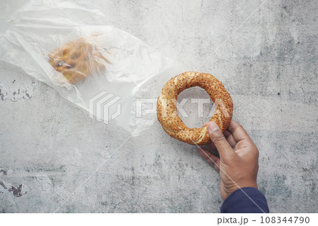 taking a Turkish Bagel Simit out from a plastic packet  108344790