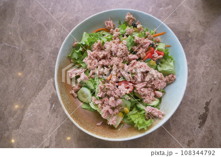 spoon pick tuna salad from a bowl on table  108344792