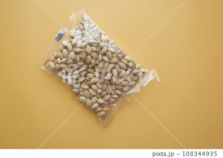 pistachios nuts in a plastic packet on orange color background pistachios nuts in a plastic packet on orange color background 108344935