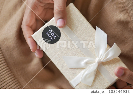 hand putting a thank you sticker on a gift box  108344938