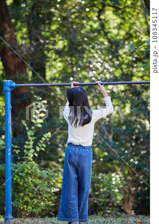 秋の公園で鉄棒を遊んでいる小学生の女の子の様子 108345117